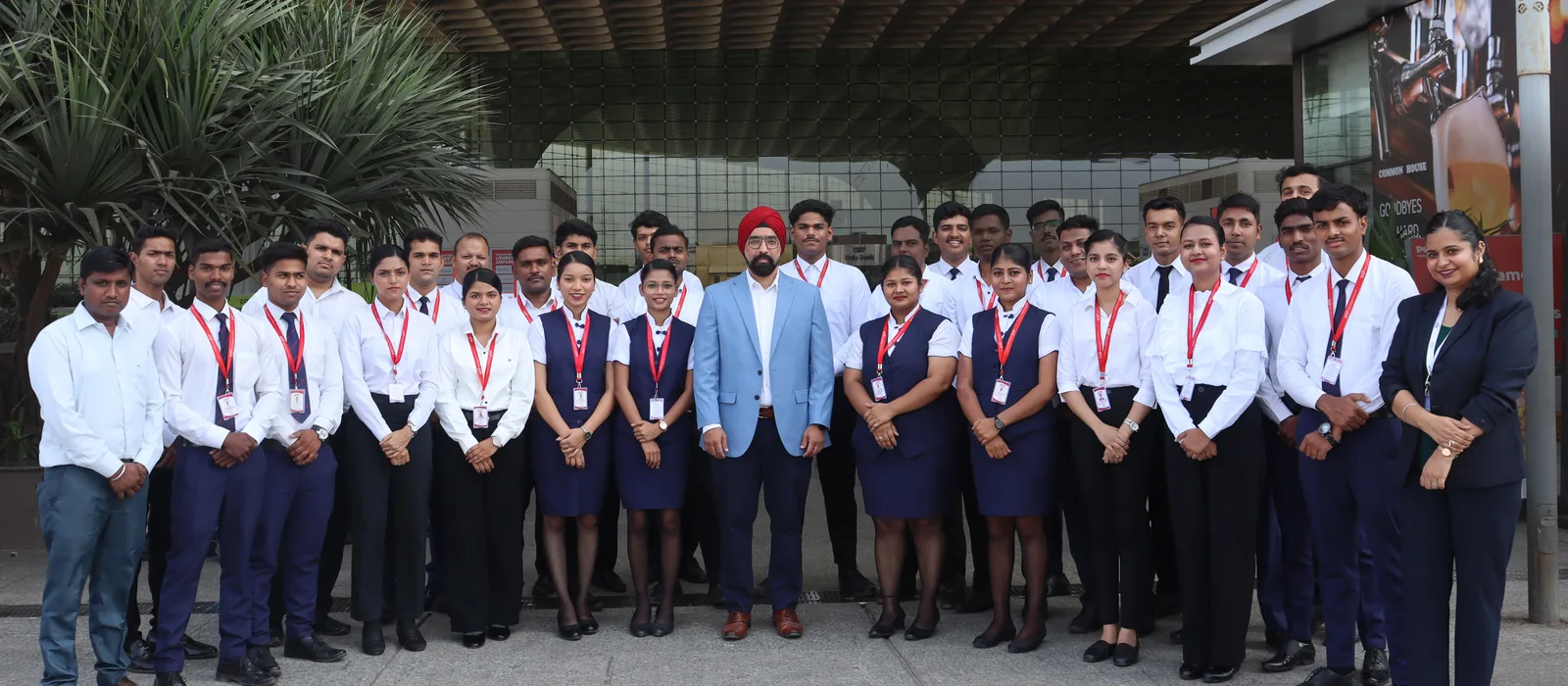 A large IESP batch in uniform with their director under the canopy at Mumbai International Airport