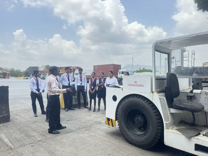 Students in uniform beside an aircraft tug