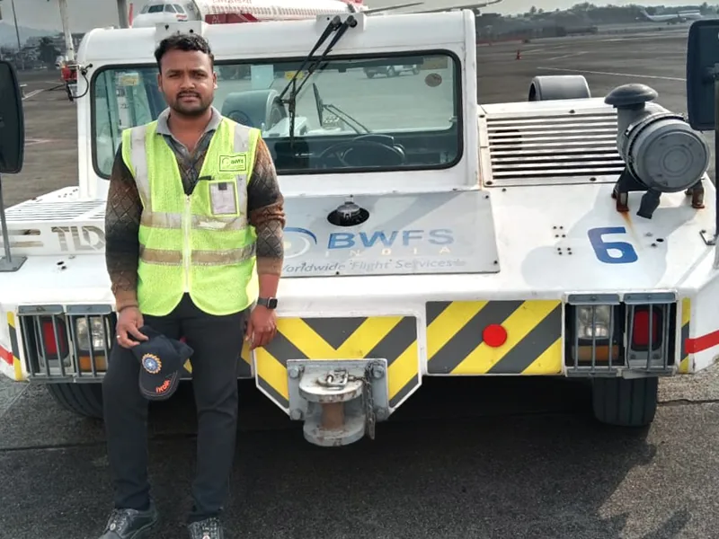 An IESP student in a high visibility vest beside an aircraft tug