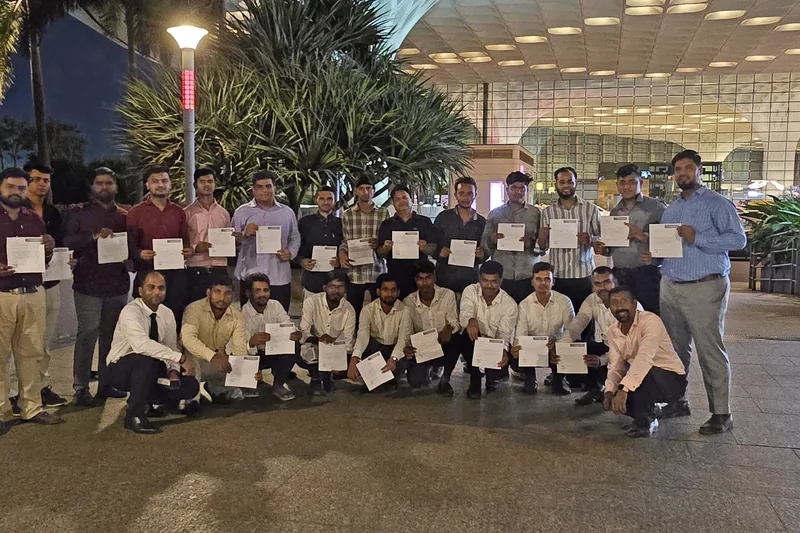 A group holding certificates outside an airport terminal at night
