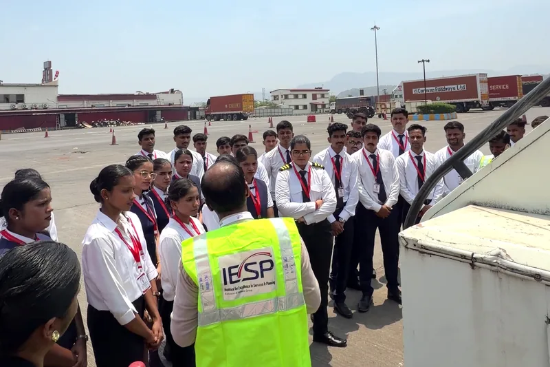 A trainer in a high visibility vest briefing students at the Khalapur centre